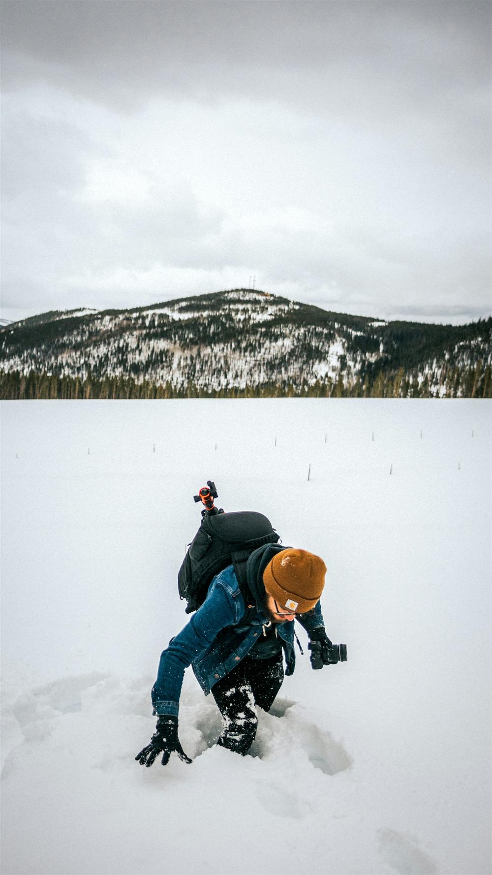 A figure climbing out of deep snow at the foot of a mountain â€” the daily struggle that this expedition is raising money to talk about.